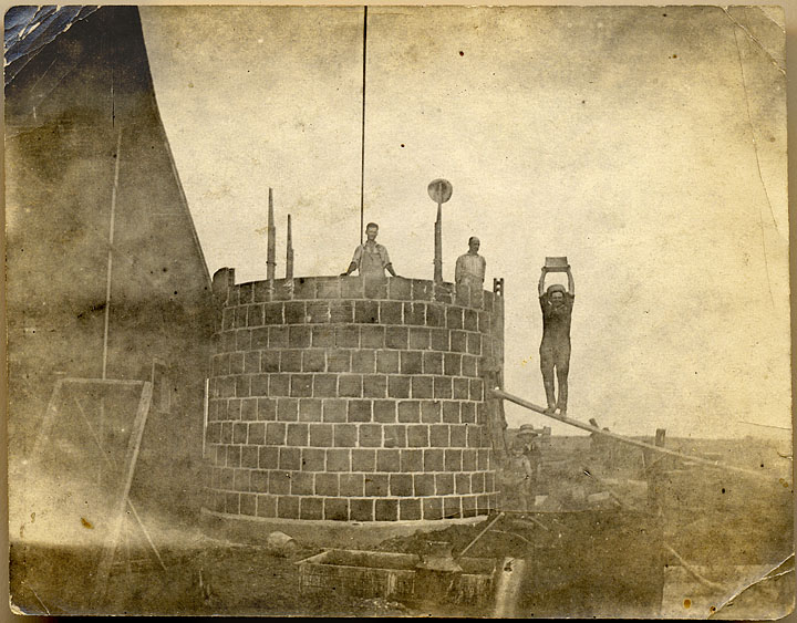 With the help of two workmen, Elmer, performing brick ballet, build a silo for the Otsego farm while Claude and Walter stand below in a most precarious location.