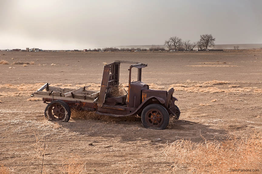 Dust blows from agricultual fields past old 1930s truck