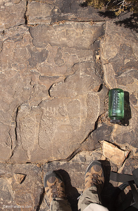 Petroglyphs of three different sized of moccasined footprints remain pecked into the rock, the smallest pair is near the crack in the top of the photo.