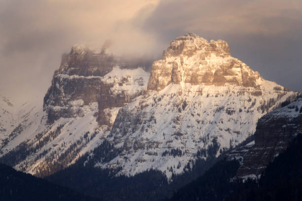 At sunset, stormy winter snow storms roll over Amphitheater Mountain in the Absaroka Mountains of Yellowstone National Park in Wyoming.
